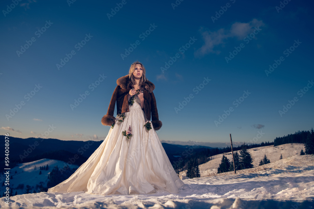 Back view of Caucasian woman wearing wedding drees and standing on snow covered field