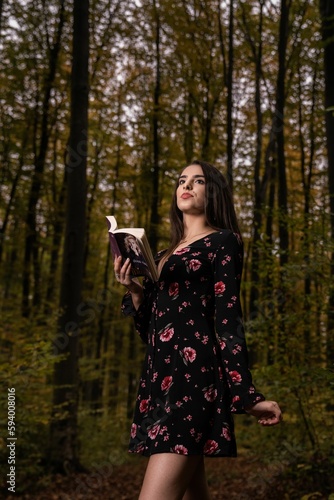 Caucasian woman holding book and standing in forest © Ionut Dragoi/Wirestock Creators
