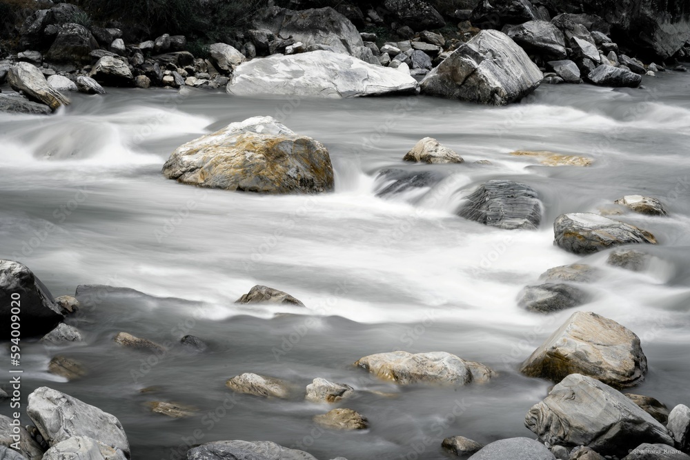 Brook stream running through a picturesque landscape of large rocky outcrops and lush greenery Brook stream running through a picturesque landscape of large rocky outcrops and lush greenery