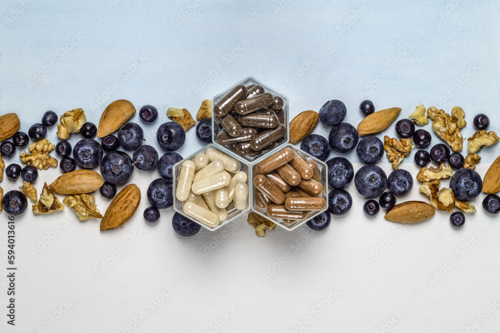 Various capsules with dietary supplements or vitamines and fresh blueberry and nuts Various capsules with dietary supplements or vitamines and fresh blueberry and nuts