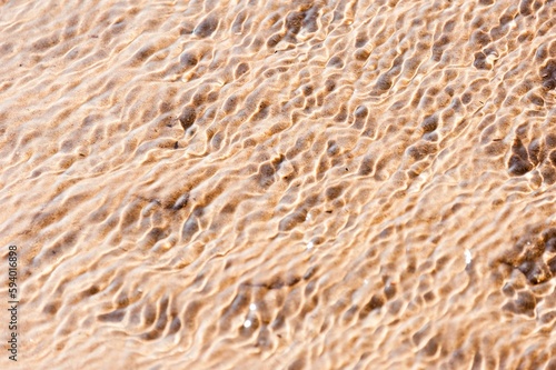 Closeup of intricate water ripples on a beach creating a mesmerizing pattern