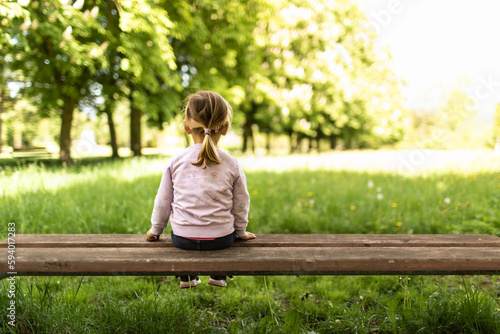 little girl sitting on a bench enjoying nature in the summer time 
