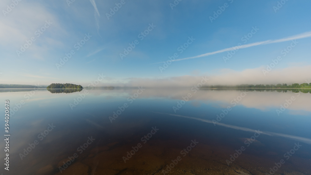 Summer lake scenery with clouds and mist reflected on the water in Finland Summer lake scenery with clouds and mist reflected on the water in Finland