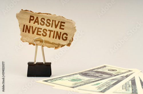 Fototapeta Naklejka Na Ścianę i Meble -  There is money on the table, next to it is a cardboard sign with the inscription - Passive Investing