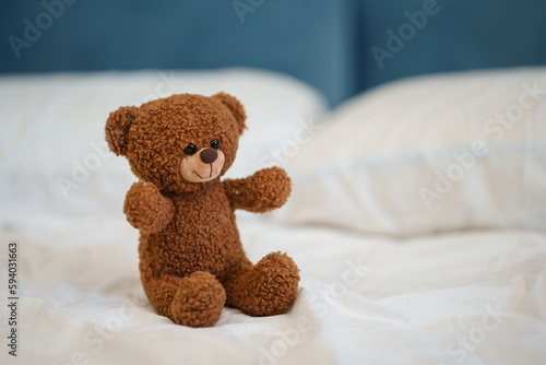 Teddy bear on a white sheet on the bed