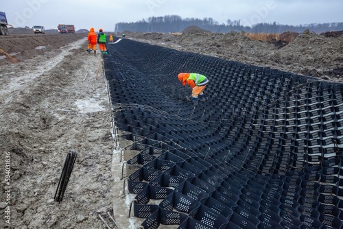 Ust-Luga, Leningrad oblast, Russia - November 16, 2021: Worker installing HDPE Geocell Ground Grid Paver. Plastic Geocell For Construction. Foreground in focus.