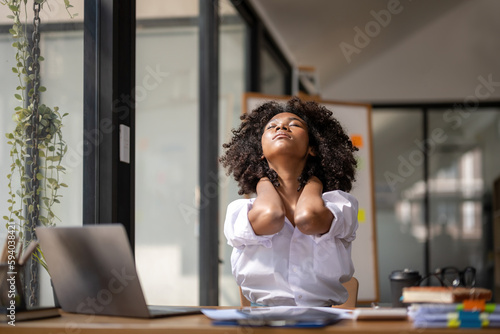 Black woman getting physically active from fatigue sitting at a desk. tired from work, Twisting due to pain, Office syndrome of office workers
