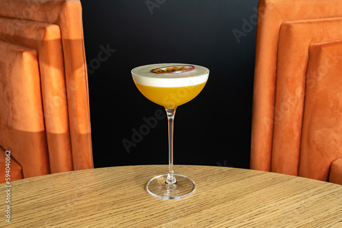 Summer cocktail garnished with passion fruit. rich yellow cold beverage on bar terrace.