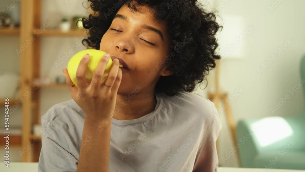Happy pretty girl biting green apple at home. Beautiful african american young woman eating fresh fruit and smiling. Healthy food vegan vegetarian dieting concept. Healthy snack clean food Happy pretty girl biting green apple at home. Beautiful african american young woman eating fresh fruit and smiling. Healthy food vegan vegetarian dieting concept. Healthy snack clean food