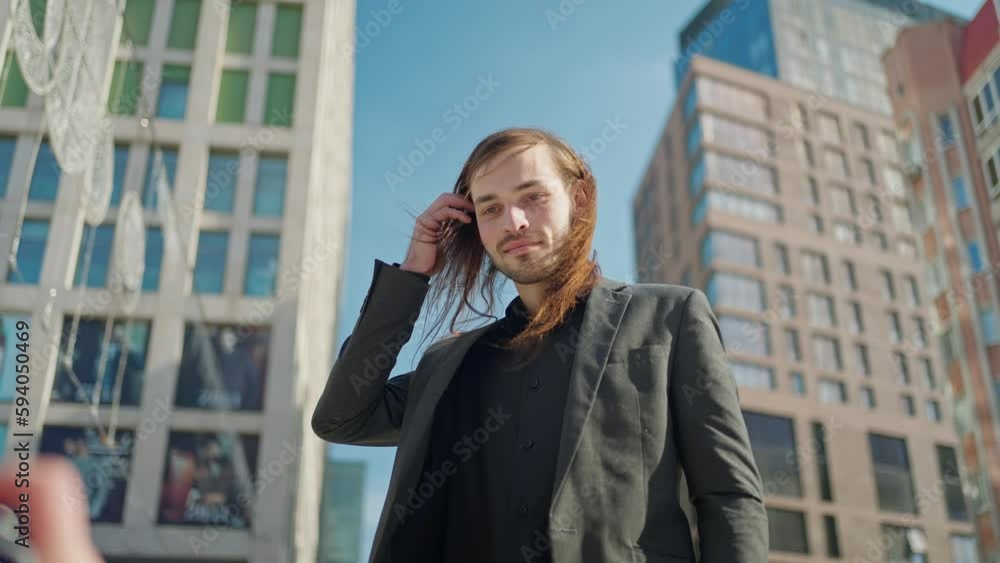 Portrait handsome man in coat looking at camera stand outdoors on background stairs. Sunlight at city street. Slow motion Portrait handsome man in coat looking at camera stand outdoors on background stairs. Sunlight at city street. Slow motion