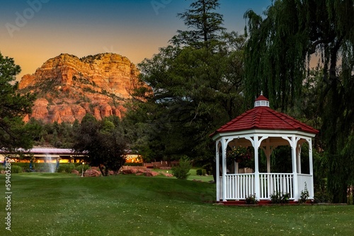 Weeping willow and gazebo with red roof on a green lawn in Sedona at sunset, AZ, USA