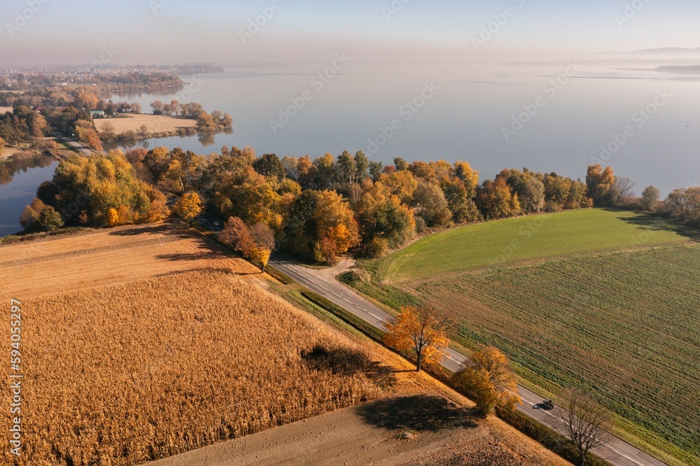 Autumn empty road near the lake and trees. Road on a sunny day in the countryside in Poland