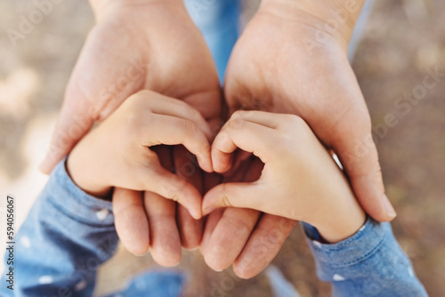 Concept Happy Mother's Day or International Day of Families. Close-up of child's hands showing shape of heart in hands of mother. Sign of love and happiness. Greeting card. Top view.