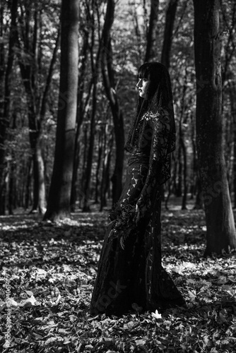 Vertical grayscale of a scary corpse bride in the autumn forest