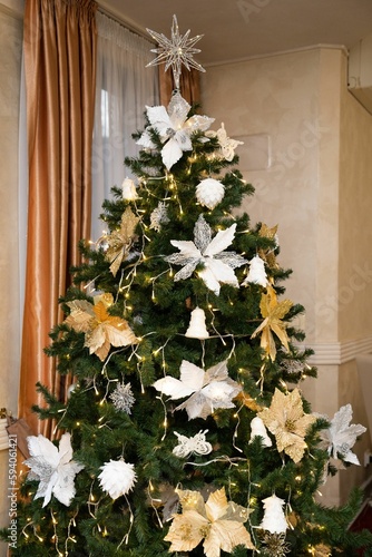 Vertical shot of a Christmas tree with white and golden aesthetic decorations