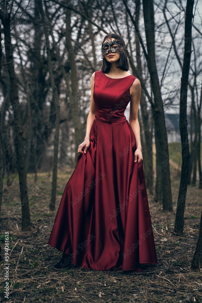 Sexy young woman in a beautiful dress and mask in a forest Sexy young woman in a beautiful dress and mask in a forest