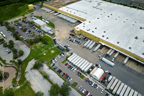 Фотография Large commercial distribution storehouse with many semitrucks unloading and uploading retail products for international shipment