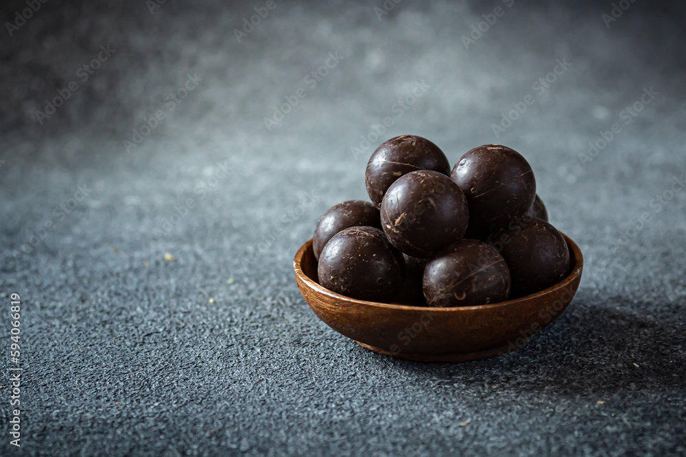 Obraz premium Small wooden plate with chocolate balls on dark blue background 