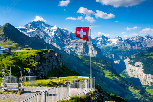 Swiss flag waving on the top of Mannlichen mountain with views of the Jungfrau region in the background