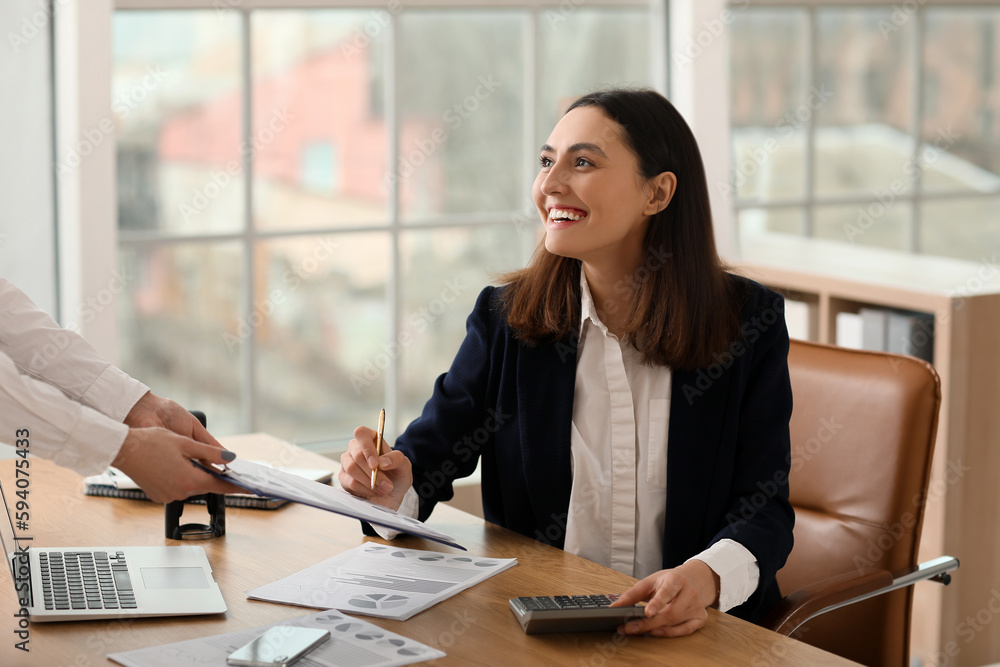 Female accountant working with colleague at table in office Female accountant working with colleague at table in office