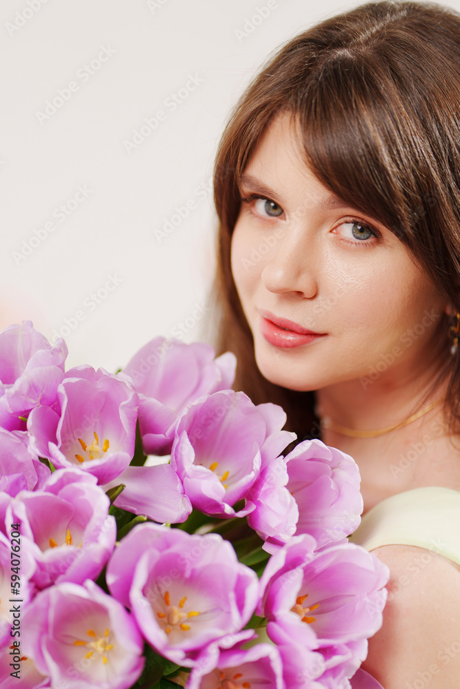 beautiful young brunette woman with long hair with a bouquet of tulips. 