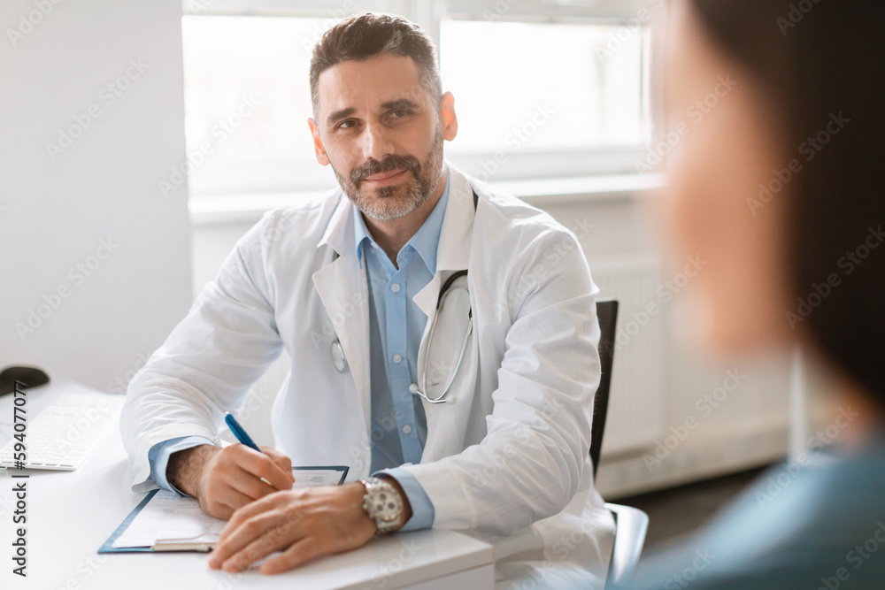 Fototapeta premium General practitioner appointment. Confident male doctor talking to female patient, discussing diagnosis and treatment