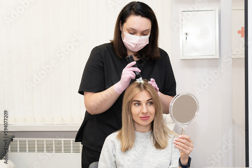 Consultation with a trichologist. Doctor examines uses trichoscope examination of the scalp and hair follicles of a caucasian female patient in a cosmetology clinic. photo