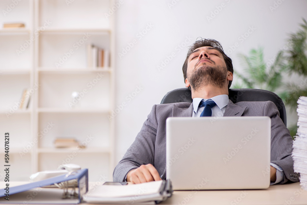 Young male employee and too much work in the office Young male employee and too much work in the office
