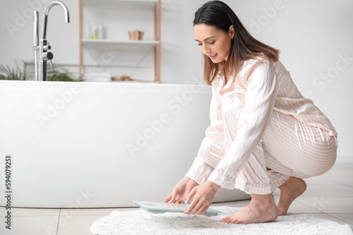 Young woman putting scales ...