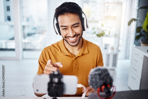 Podcast  pointing and live streaming with a man influencer recording broadcast content in his home office. Internet  streamer and subscription with a male freelancer or creator working in his studio