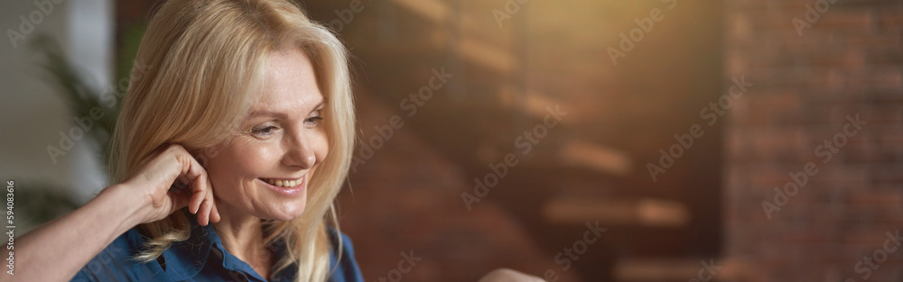 Smiling mature woman watching video using digital tablet pc, relaxing on a couch at home in the living room Smiling mature woman watching video using digital tablet pc, relaxing on a couch at home in the living room