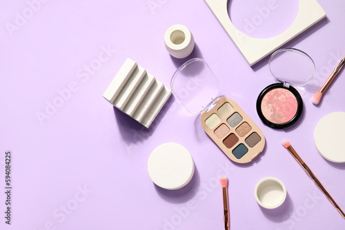 Eyeshadows with highlighter, brushes and podiums on lilac background