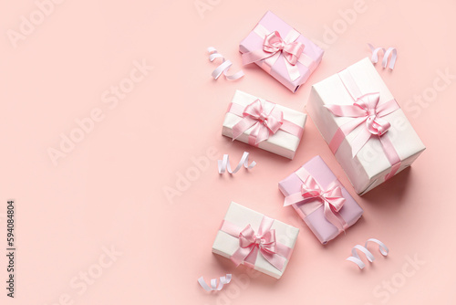 Gift boxes with beautiful bows and serpentine on pink background © Pixel-Shot