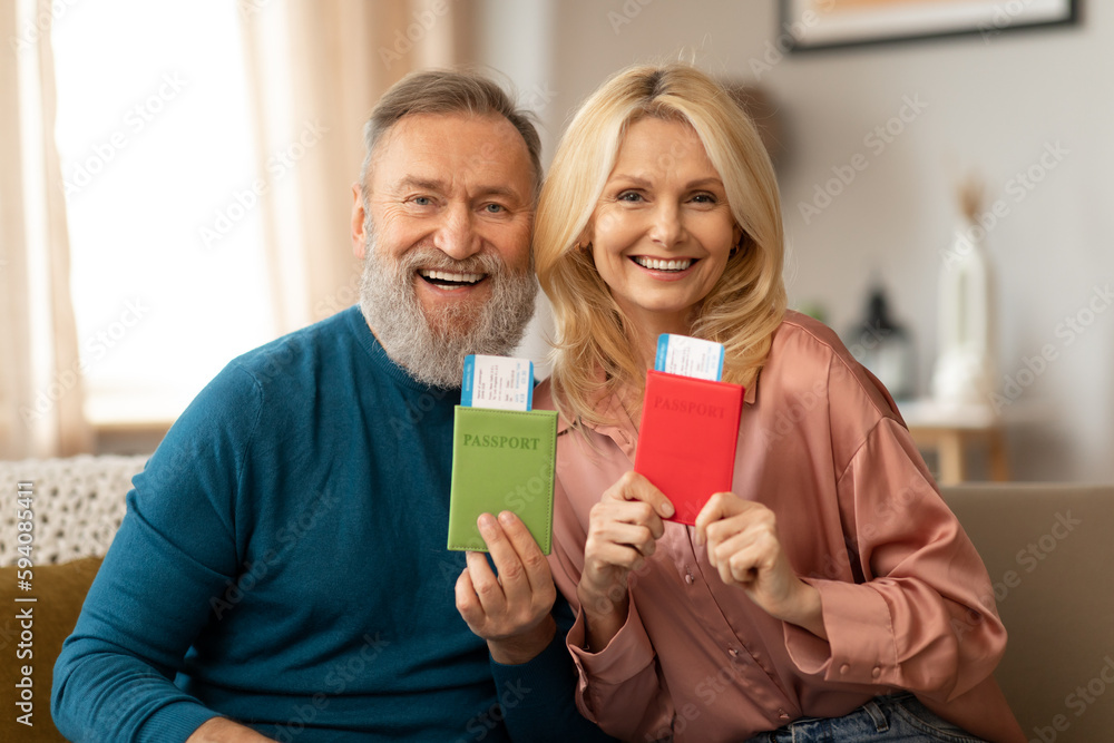 Happy Mature Couple Showing Passports With Boarding Passes Tickets Indoors