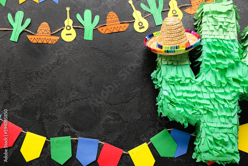 Frame made of Mexican pinata, sombrero hat, garland and flags on dark background