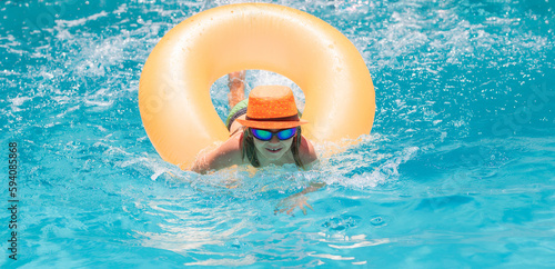 Child splashing in swimming pool. Swim water sport activity on summer vacation with child. Kids water toys.