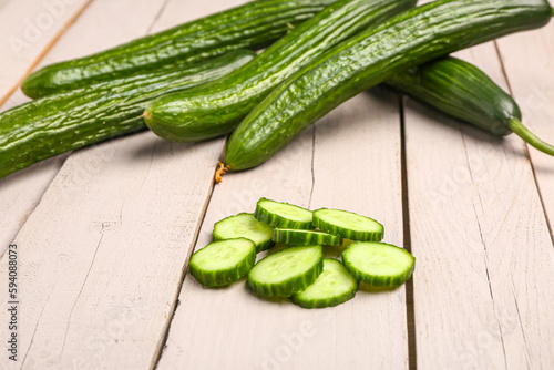Slices of fresh cut cucumber on light wooden background
