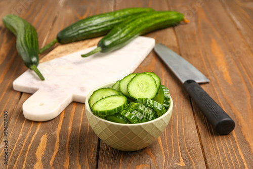 Bowl with fresh cut cucumber on wooden background