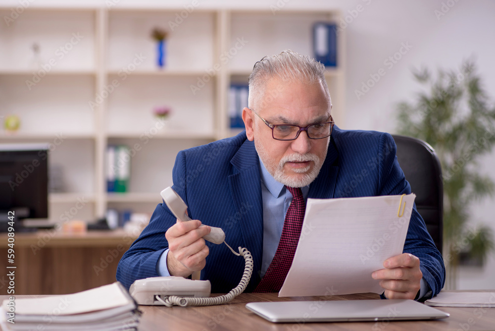 Old male employee working in the office Old male employee working in the office