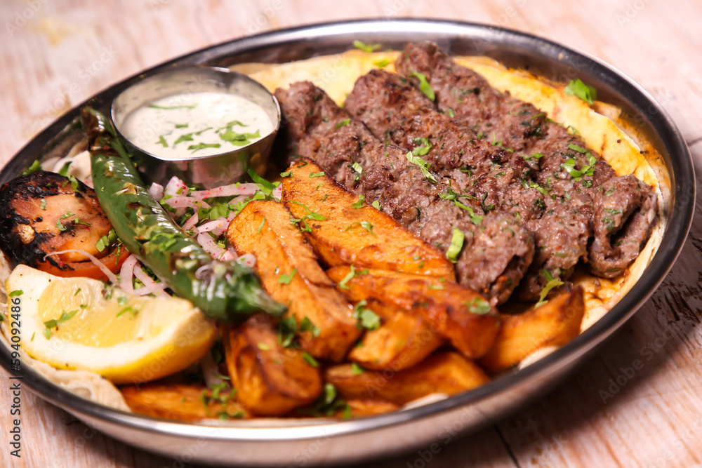 Kebab Laham or lamb kabab with salad, wedges, lemon and dip served in dish isolated on background top view of arabic food Kebab Laham or lamb kabab with salad, wedges, lemon and dip served in dish isolated on background top view of arabic food