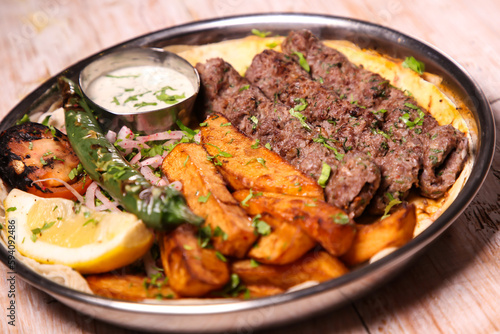 Kebab Laham or lamb kabab with salad, wedges, lemon and dip served in dish isolated on background top view of arabic food