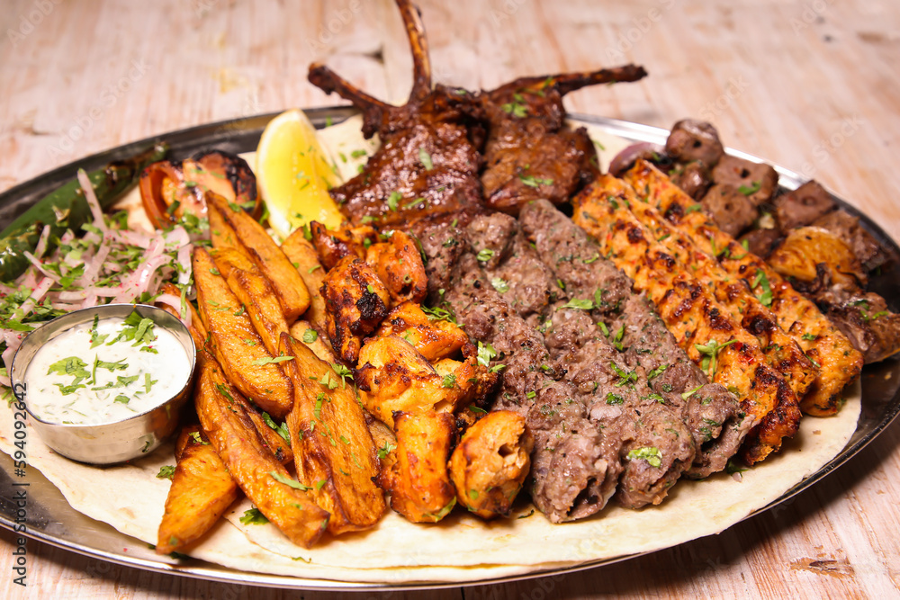Assorted mix grills with chicken tikka, beef kabab, mutton kebab, wings, boti, malai, chop, shish tawook served in dish isolated on background top view of arabic food