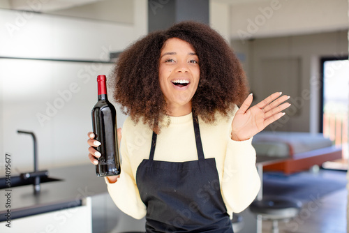 pretty afro black woman feeling happy and astonished at something unbelievable. wine bottle concept