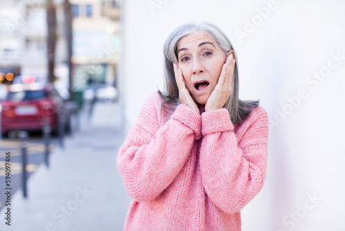 senior retired pretty white hair woman feeling shocked and scared, looking terrified with open mouth and hands on cheeks © kues1