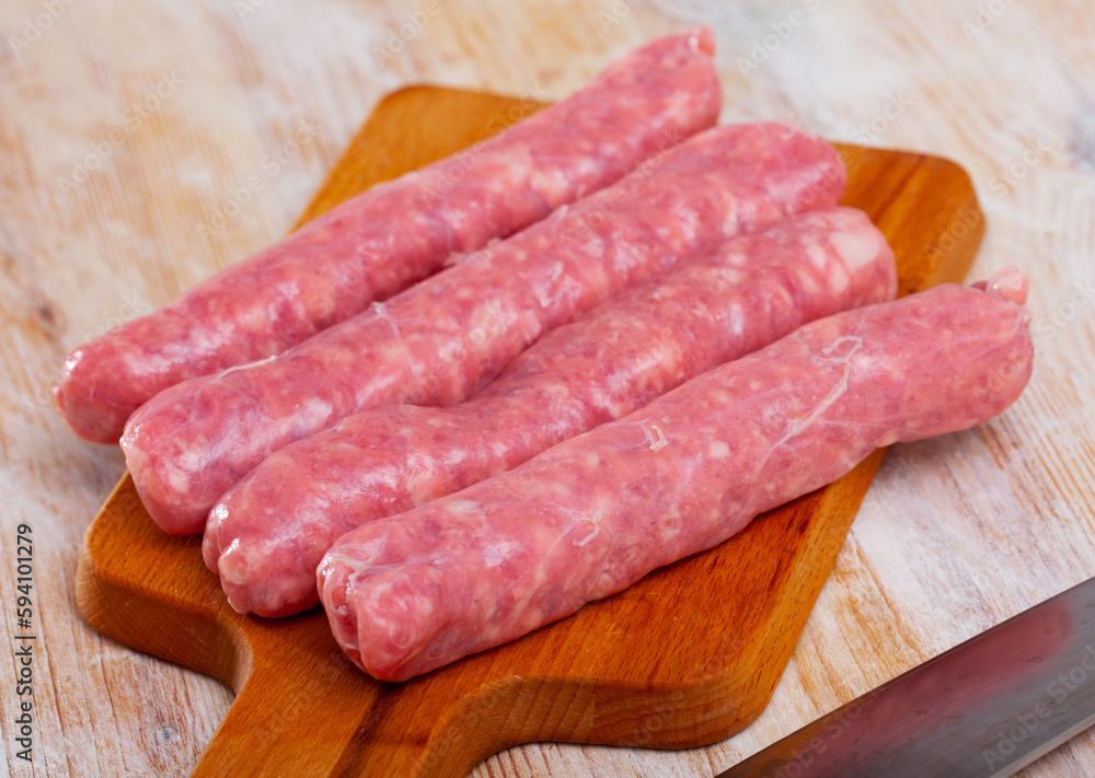 Raw spicy sausages ready for cooking on wooden surface