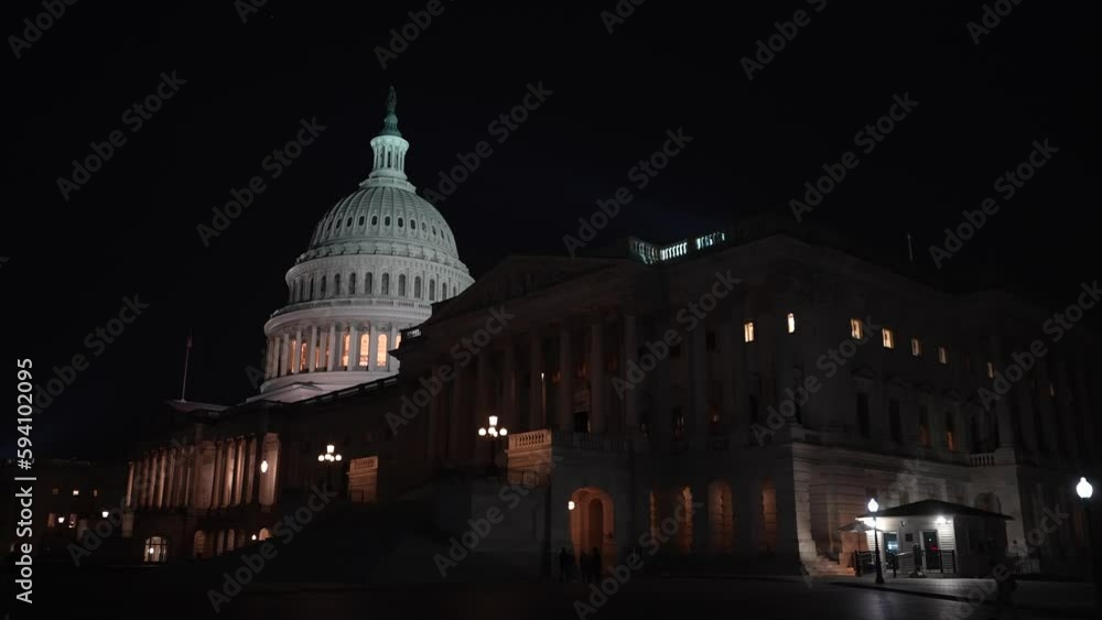 Moving camera showing the US Capitol with lights and flags waving in Washington DC at night set against a blue purple sky. Moving camera showing the US Capitol with lights and flags waving in Washington DC at night set against a blue purple sky.