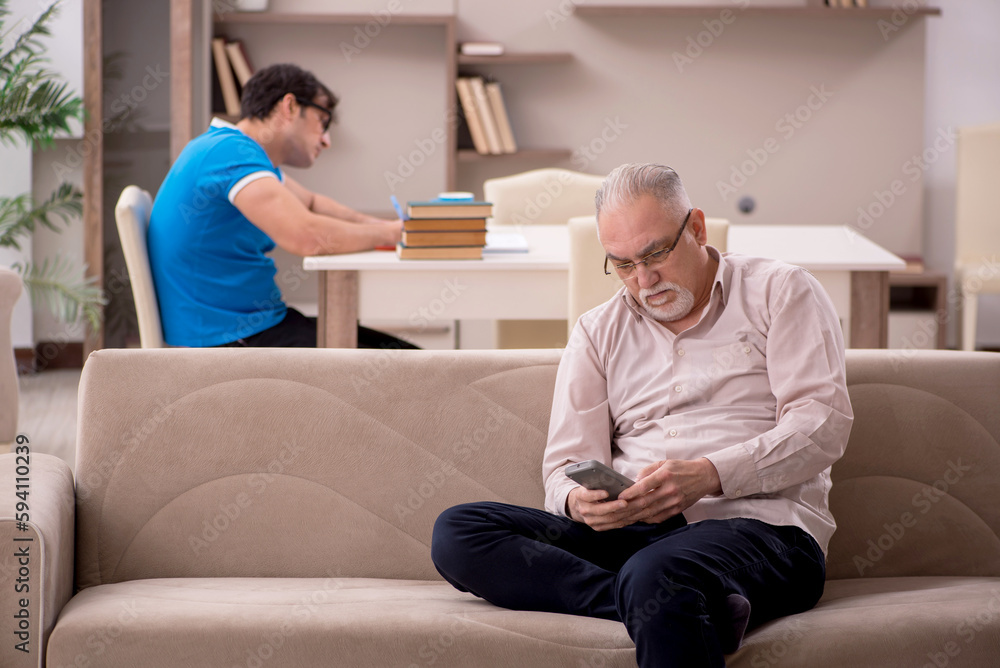 Obraz premium Young male student and his grandfather at home