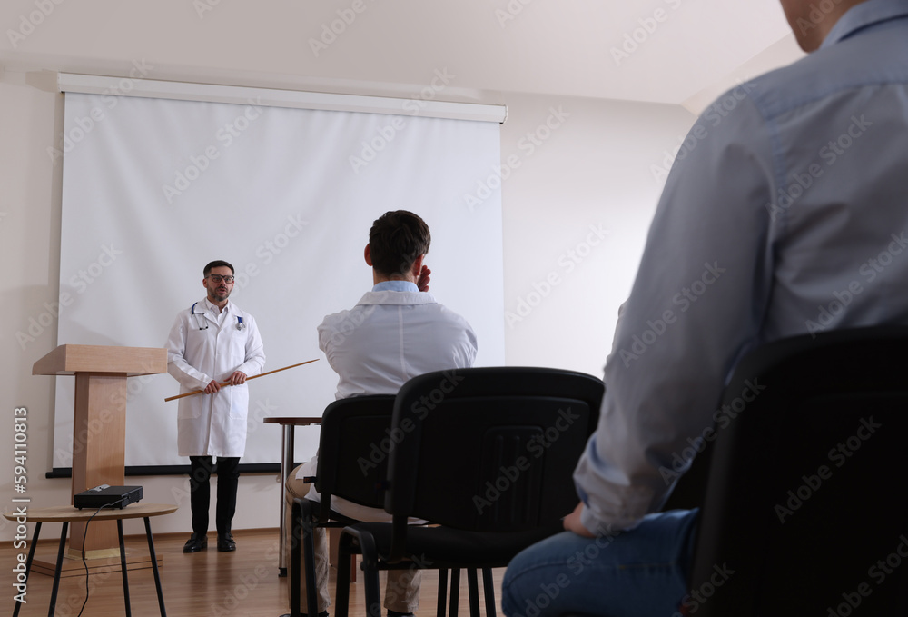 Doctor giving lecture in conference room with projection screen Doctor giving lecture in conference room with projection screen