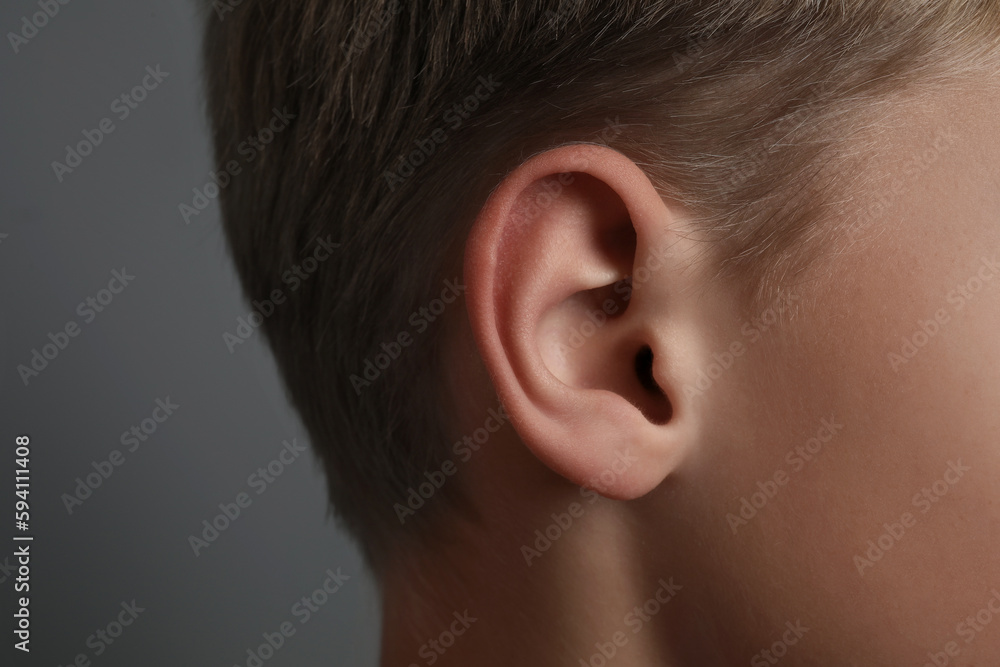 Boy on grey background, closeup of ear Boy on grey background, closeup of ear