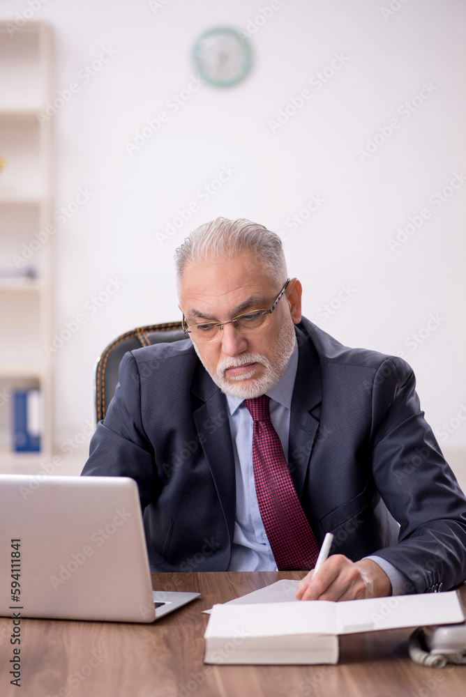 Old male boss working at workplace Old male boss working at workplace